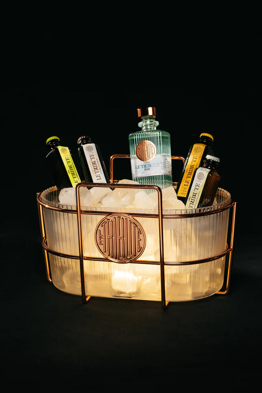 LE Tribute Gin and mixer bottles chilling in a stylish copper ice bucket with art deco ribbed design and ambient lighting