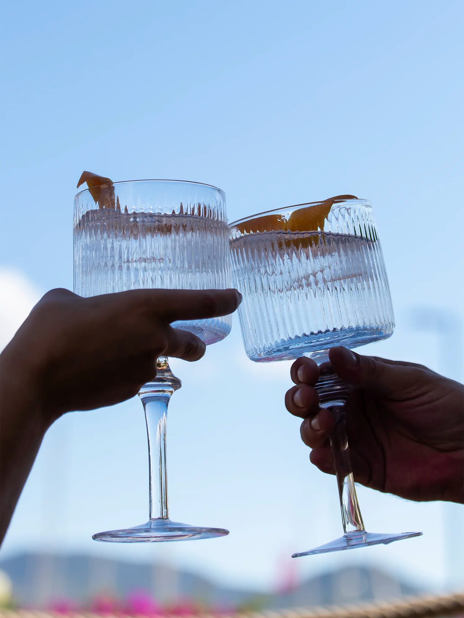 LE Tribute branded crystal coupe glasses clinking in a celebratory toast, perfect for outdoor gatherings