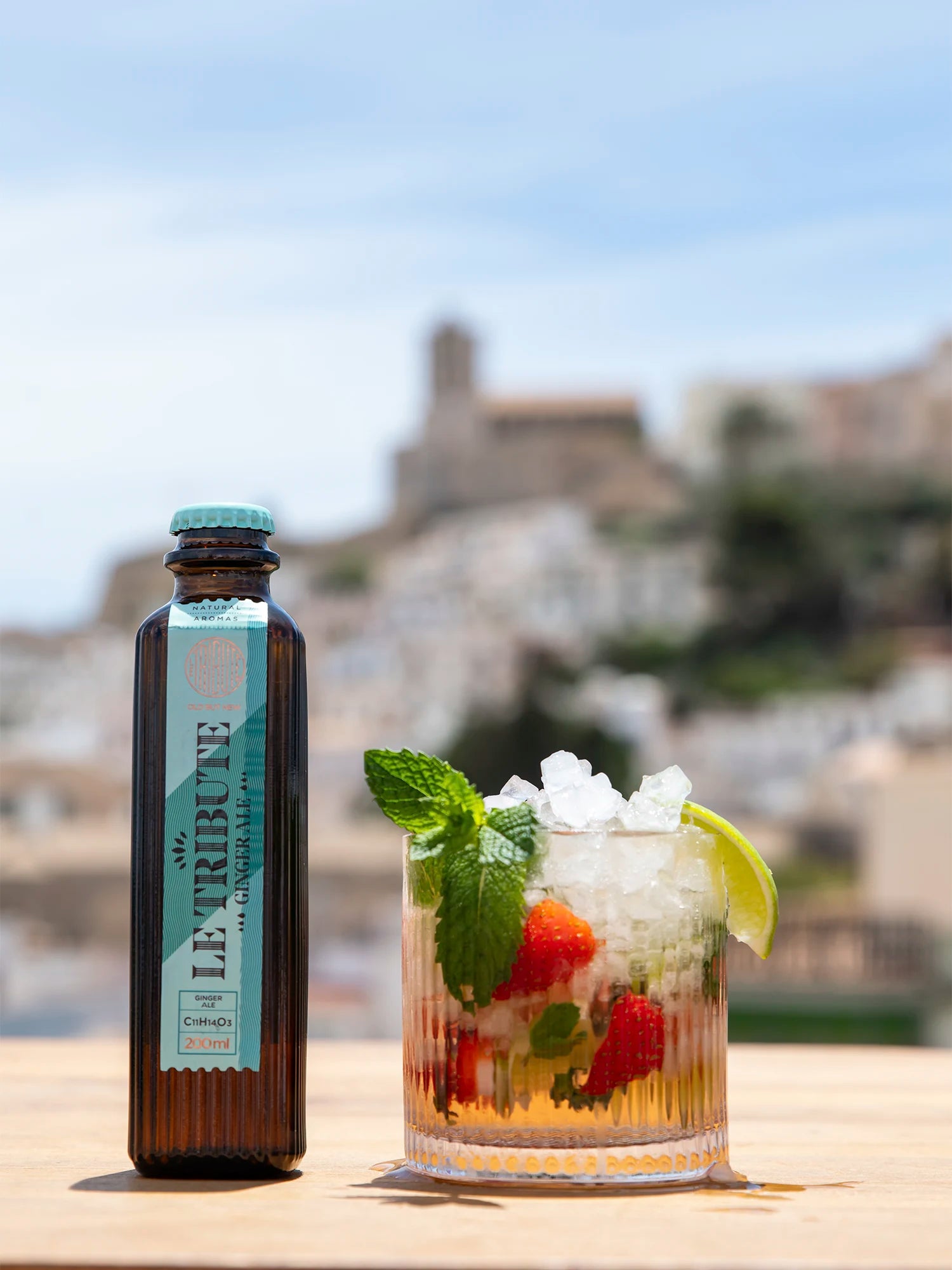 LE Tribute Ginger Ale bottle next to a refreshing strawberry and mint cocktail, perfect for a sunny day