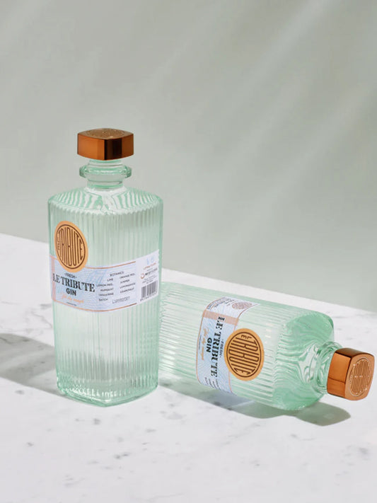 Two LE Tribute Gin bottles, one upright and one lying down, showcasing the signature ribbed glass design