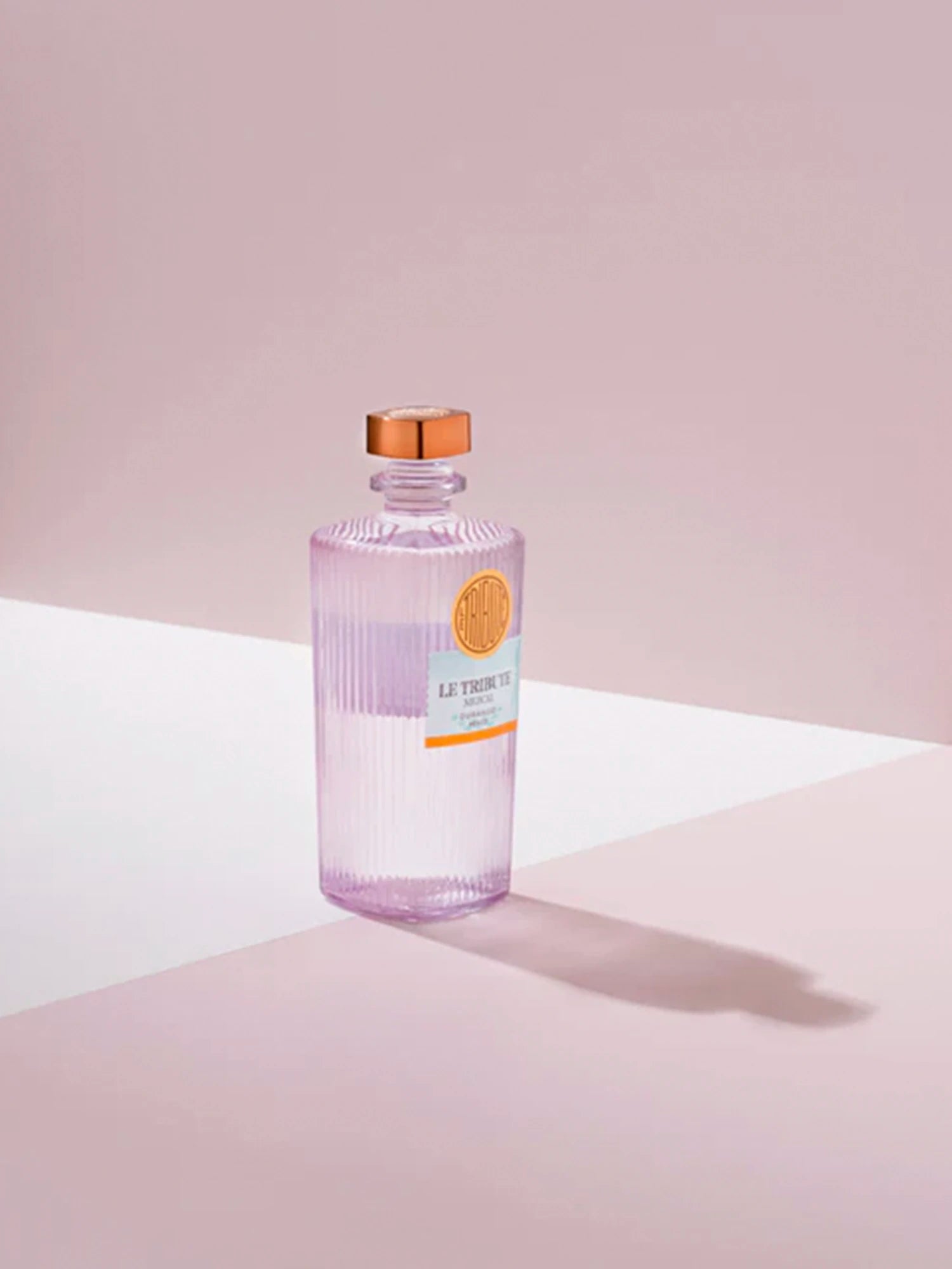 LE Tribute Mezcal bottle in a dramatic setting with soft lighting and deep pink background, emphasizing its premium quality