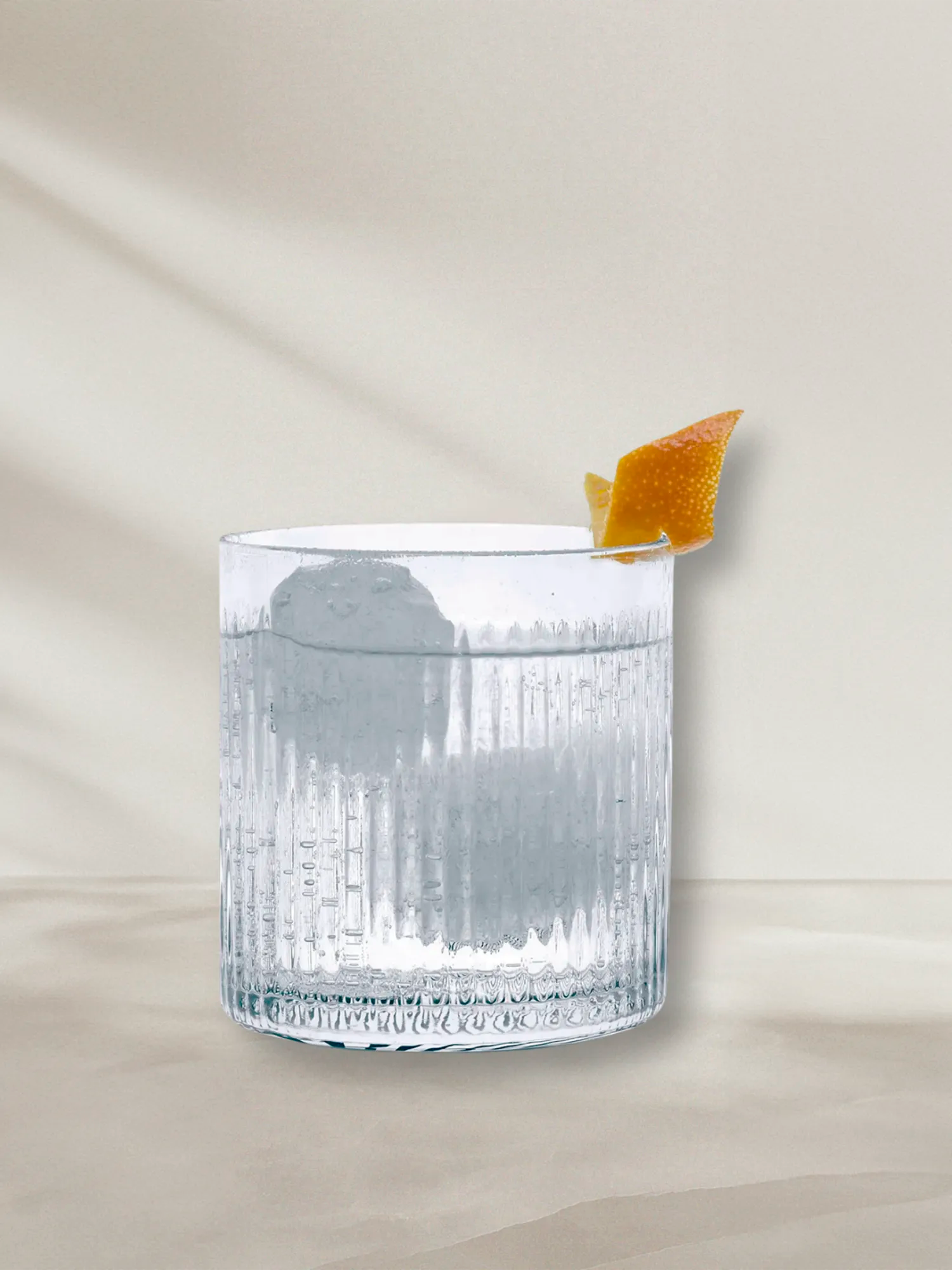 LE Tribute branded glass filled with a refreshing cocktail and citrus garnish, styled with natural light