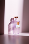LE Tribute Mezcal bottle standing tall on a soft pink surface, highlighting its clean, elegant design