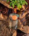 LE Tribute Gin surrounded by natural botanicals: lavender, juniper berries, cardamom, and sage
