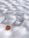 LE Tribute branded crystal glasses and copper accessory, presented on a marble surface with light and shadow play